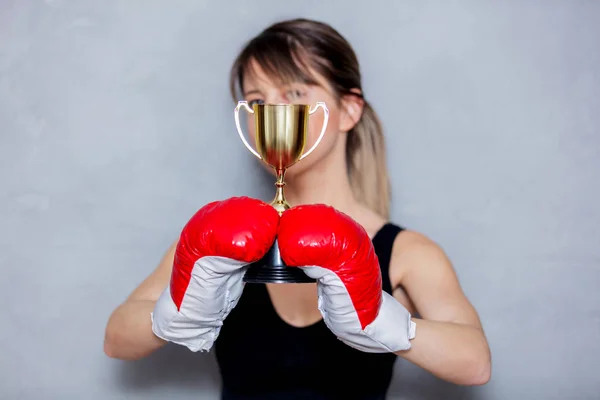 Jeune femme en gants de boxe avec tasse dorée — Photo