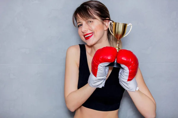 Jovem mulher em luvas de boxe com copo dourado — Fotografia de Stock