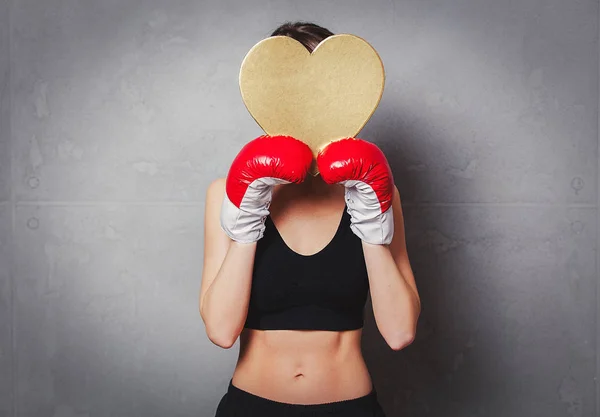 Mulher em luvas de boxe com forma de coração caixa de presente em mãos — Fotografia de Stock