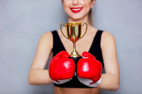 Jeune femme en gants de boxe avec tasse dorée — Photo