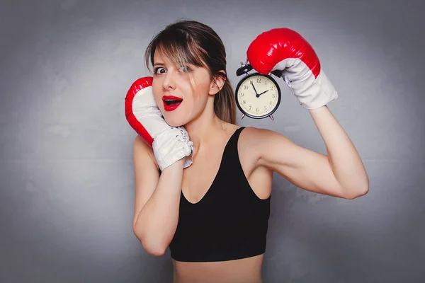 Jovem mulher em luvas de boxe com despertador — Fotografia de Stock