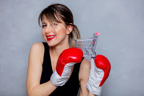 Ung kvinna i boxning handskar med kundvagn — Stockfoto