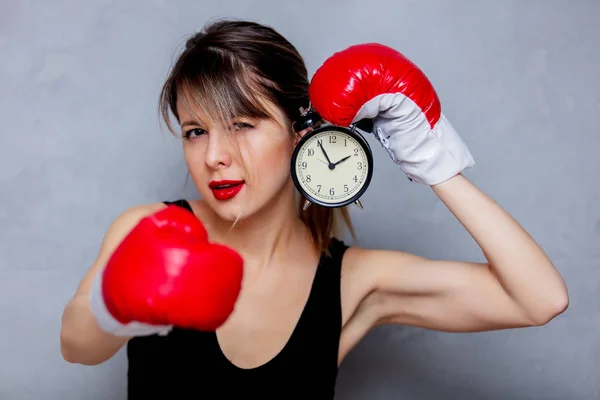 Jovem mulher em luvas de boxe com despertador — Fotografia de Stock