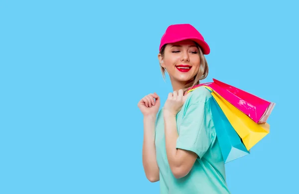 Meisje in blauw t-shirt met shopping tassen — Stockfoto