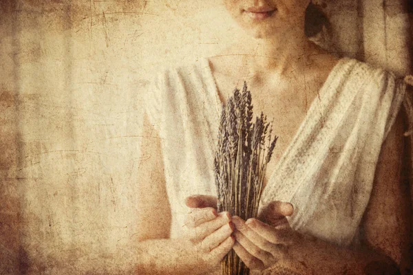 Woman in white dress holding lavender near window — Stock Photo, Image