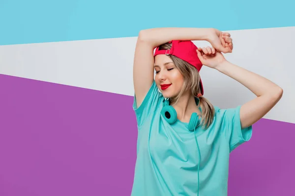 Menina de boné rosa e camiseta azul com fones de ouvido — Fotografia de Stock