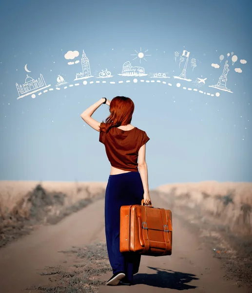 Redhead girl with suitcase at countryside road — Stock Photo, Image