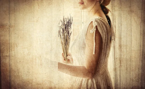 Woman in white dress holding lavender near window — Stock Photo, Image