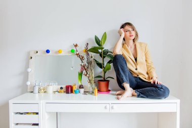 ayna ve bitki yakınındaki bir masada oturan kadın