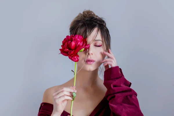 Female in red shirt holing red peony — Stock Photo, Image