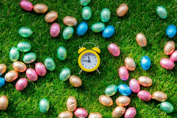 Színes csokoládé húsvéti tojások és ébresztőóra — Stock Fotó