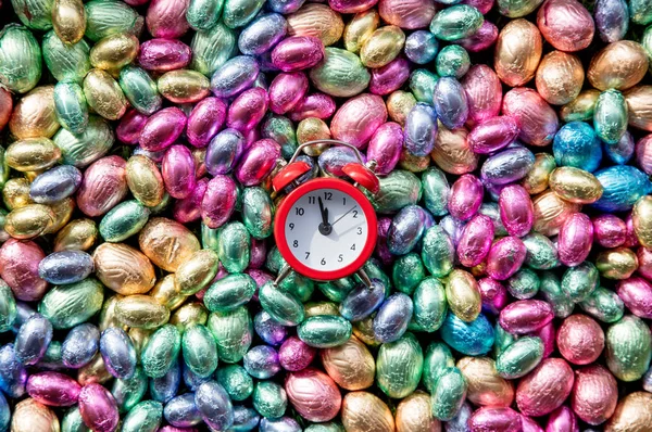 Olor Chocolate Easter eggs and alarm clock on it — Stock Photo, Image