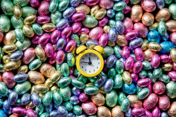 Olor Chocolate Easter eggs and alarm clock on it — Stock Photo, Image