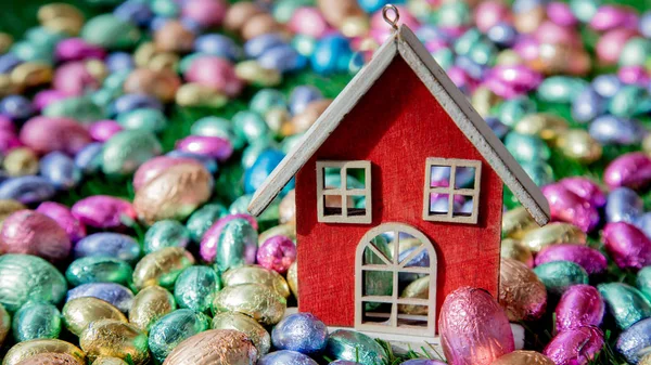 Czekoladowe jaja wielkanocne i dom zabawka na nim — Zdjęcie stockowe