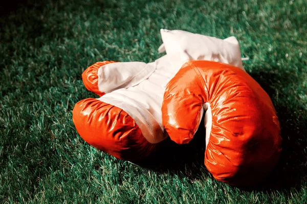 Rote Boxhandschuhe auf grünem Gras. — Stockfoto