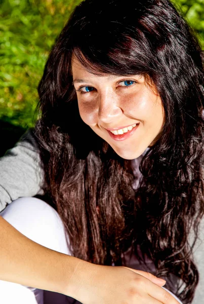 Portret van mooie brunette meisje met blauwe ogen op groen gras — Stockfoto