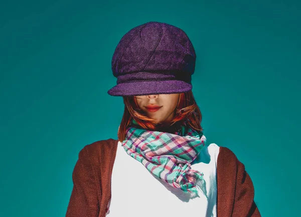 Portrait of red-haired girl with scarf and purple cap on blue sk — Stock Photo, Image