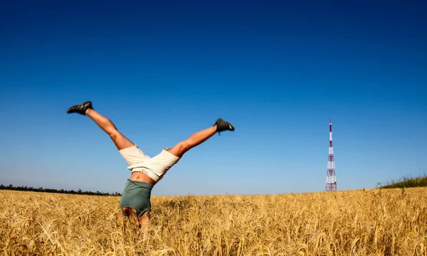 Hembra con pies hacia arriba haciendo acrobacia en el campo de trigo —  Fotos de Stock