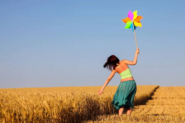 Mladá žena s hračkou Větrník na pšeničné pole. — Stock fotografie