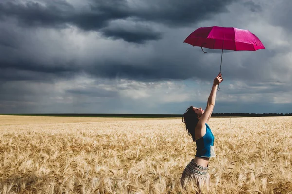 Mujer joven con paraguas en el campo de trigo en tiempo de tormenta —  Fotos de Stock