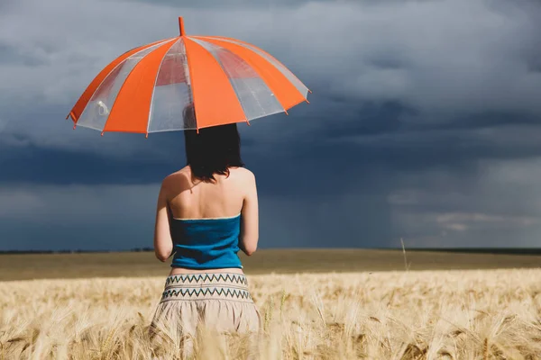 Giovane donna con ombrello sul campo di grano in tempo di tempesta — Foto Stock