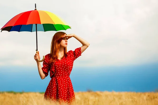 Руда дівчина з парасолькою на полі — стокове фото