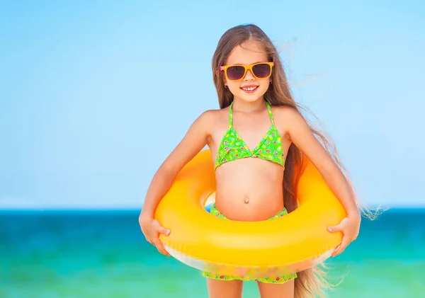 Criança com óculos de sol e anel inflável na praia — Fotografia de Stock