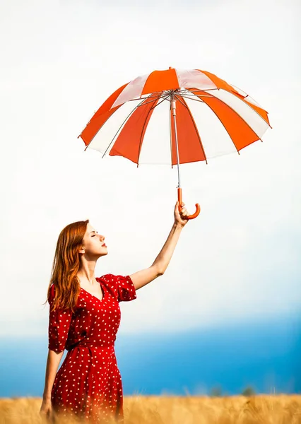 Rusovláska dívka s deštníkem na pole — Stock fotografie