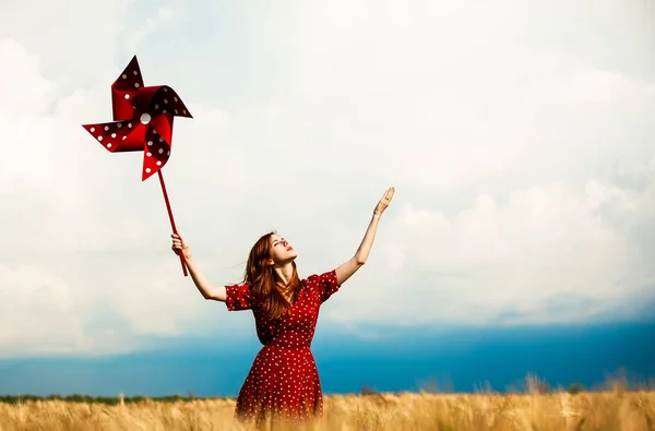 Redhead κορίτσι με pinwheel παιχνίδι στο σιτάρι που κατατίθεται σε θερινή ώρα — Φωτογραφία Αρχείου