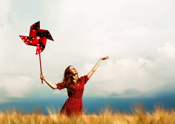 Zrzka holka s hračkou Větrník na pšenici podané v letním období — Stock fotografie