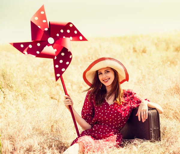 Roodharige meisje met pinwheel speelgoed op tarwe geplaatst — Stockfoto