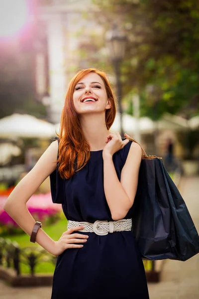 Mujer joven con bolsas de compras caminando por la calle de la ciudad — Foto de Stock