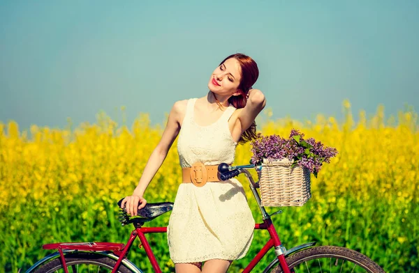 Roodharige meisje met fiets en bloemen in mand — Stockfoto