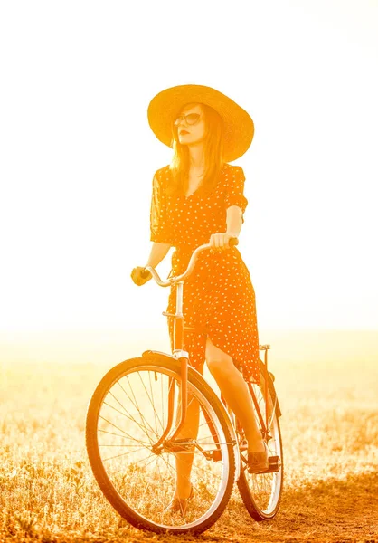 Chica en una bicicleta en el campo en el amanecer — Foto de Stock