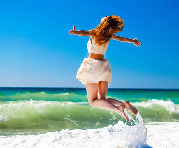 Mladá rusovláska dívka, která skočila na pláži. — Stock fotografie