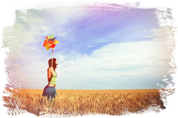 Young woman with pinwheel toy on wheat field — Stock Photo, Image