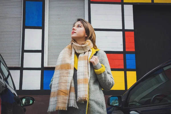 Στυλ κορίτσι με κασκόλ και παλτό μείνετε ανάμεσα στα αυτοκίνητα — Φωτογραφία Αρχείου