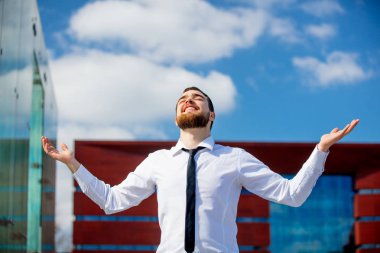 Young businessman with open arms at city outdoor 