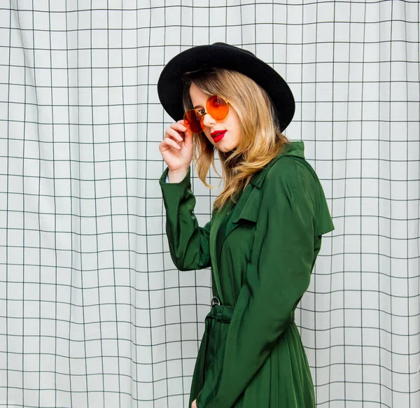 Jonge vrouw in zonnebril en groene mantel in de jaren 90 stijl stijl — Stockfoto