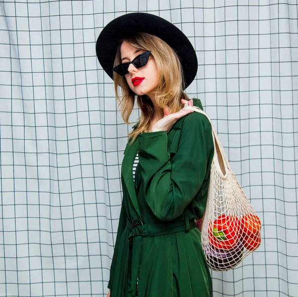 Vrouw in hoed en groene mantel in de jaren 90 stijl met netto tas — Stockfoto