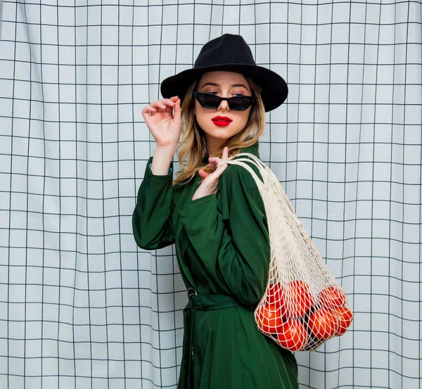 Frau mit Hut und grünem Mantel im 90er-Jahre-Stil mit Netztasche — Stockfoto