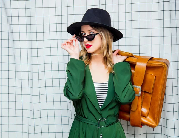 Kvinna i hatt och grön mantel i 90-talet stil med resor resväska — Stockfoto