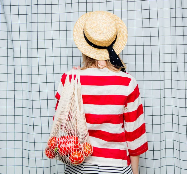 Mujer sonriente en sombrero y chaqueta a rayas con bolsa de red —  Fotos de Stock