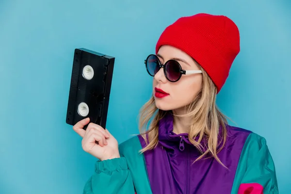 Mulher de chapéu vermelho, óculos de sol e terno dos anos 90 com cassete VHS — Fotografia de Stock
