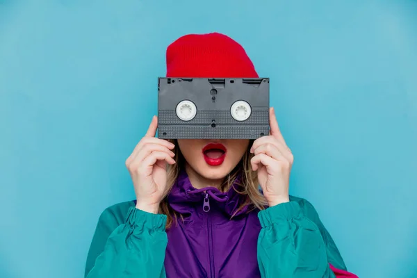 Mujer en sombrero rojo, gafas de sol y traje de los años 90 con cassette VHS —  Fotos de Stock