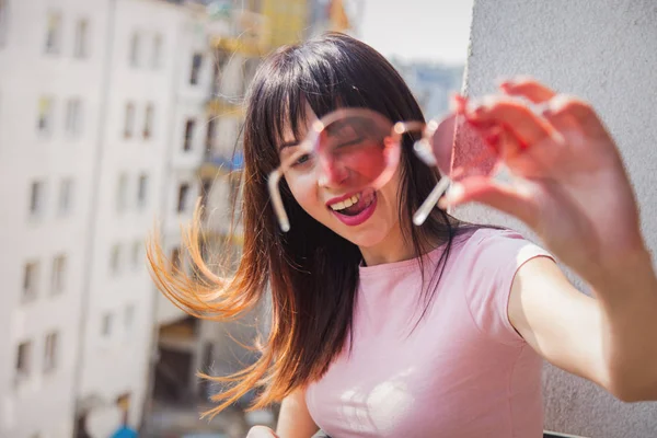 Genç kadın güneş gözlüğü ile bir kamera bakıyor — Stok fotoğraf