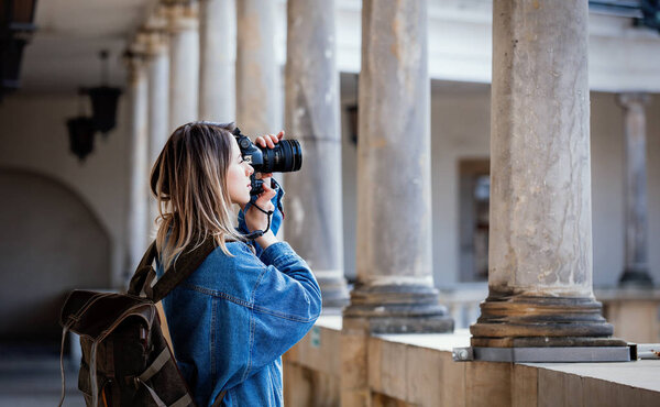 Young woman, professional photographer with camera in old castle