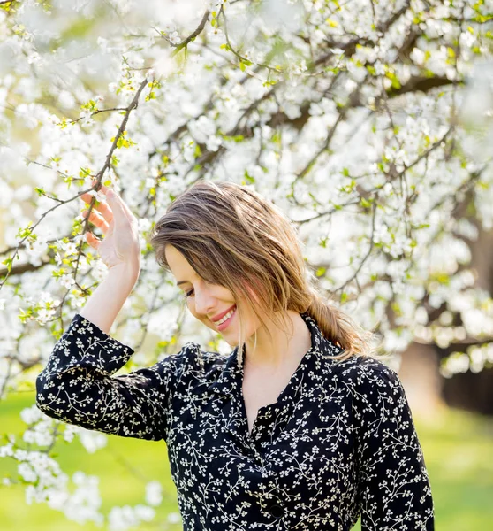 Giovane ragazza in abito scuro stare vicino a un albero in fiore — Foto Stock