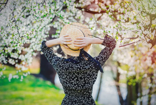 Jovem em um chapéu ficar perto de uma árvore de floração — Fotografia de Stock