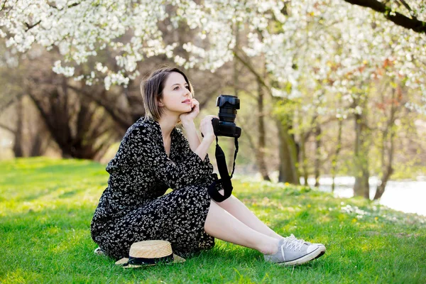 Mladá dívka s fotoaparátem v blízkosti kvetoucího stromu — Stock fotografie